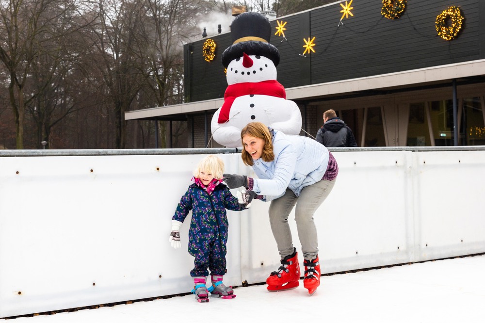 Moeder en kind schaatsen op ijsbaan tijdens kerstvakantie